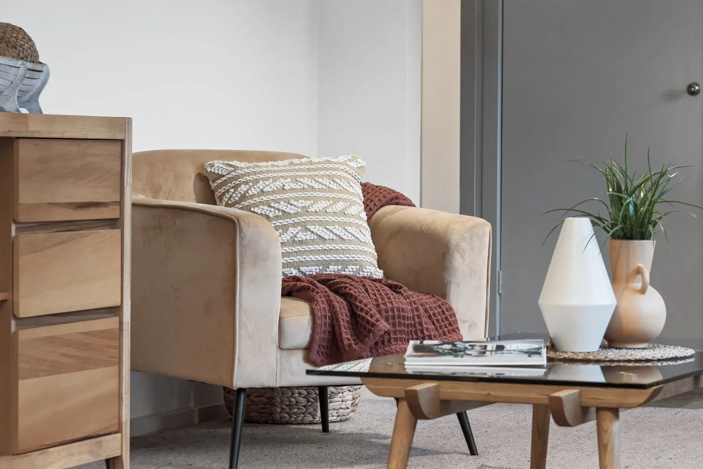 A warm armchair with a soft throw and plants in gentle daylight