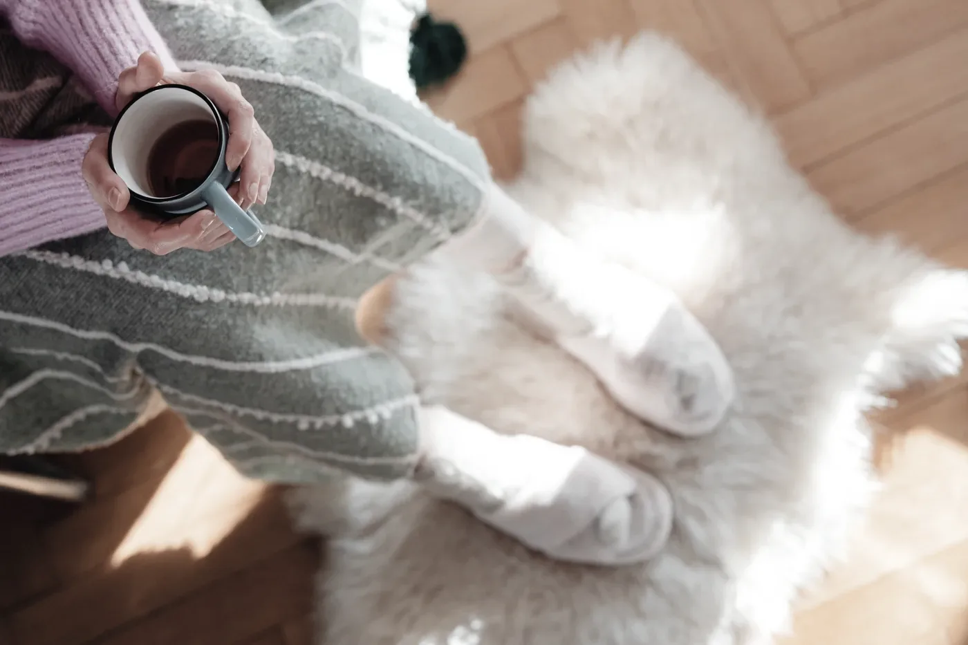A person sitting quietly with a warm cup of tea in soft daylight